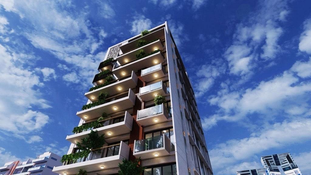 Low-angle render of a BuildCraft residence with cantilevered, planted balconies against a blue sky